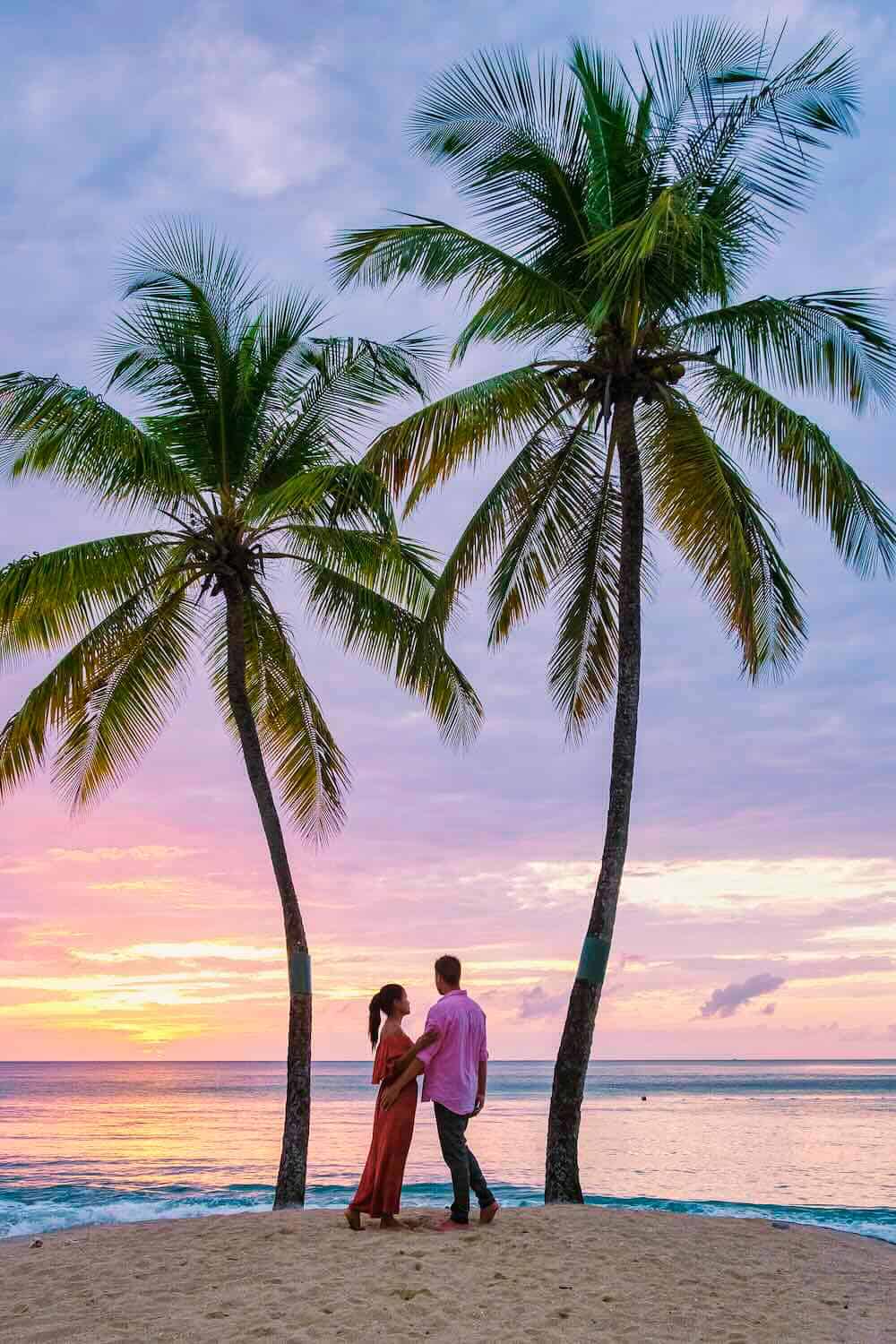 Palm trees on tropical beach at sunset with romantic couple, travel destination, vacation, honeymoon, I Do Destinations by vivid.
