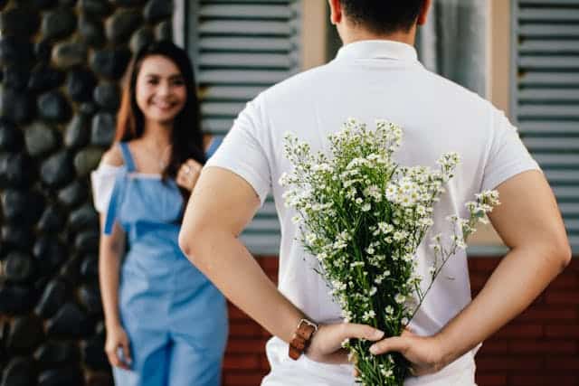 Beautiful couple moment for romantic getaway travel planning, with a woman holding flowers behind her partner. Perfect for vacation destinations, love trips, and destination wedding inspiration.