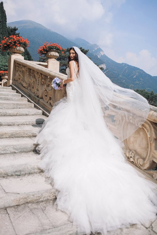 Elegant bride in a wedding dress on a scenic mountain staircase during a destination wedding at I Do Destinations by vivid.