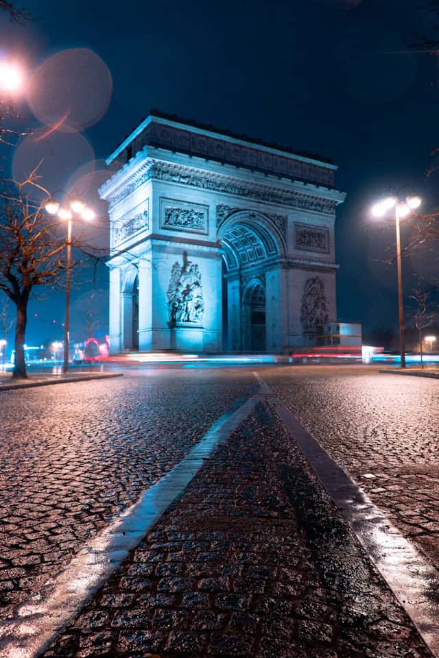 Iconic Arc de Triomphe illuminated at night in Paris, France, showcasing romantic travel destinations and European landmarks.
