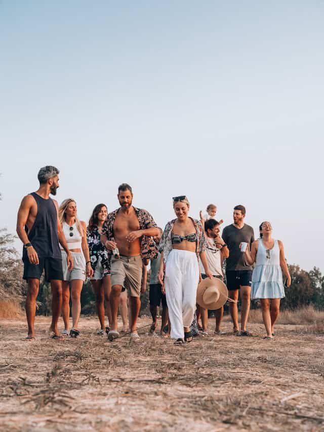 Relaxed group of friends enjoying a destination wedding, walking outdoors in a natural setting with clear skies, showcasing travel and destination wedding experience.